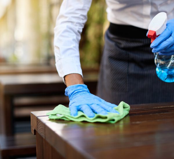 Close-up of waitress disinfecting tables at outdoor cafe during coronavirus epidemic.