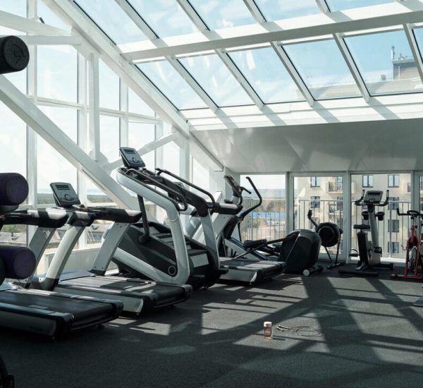 Horizontal no people wide shot of various exercise machines in modern gym with panoramic windows in daylight