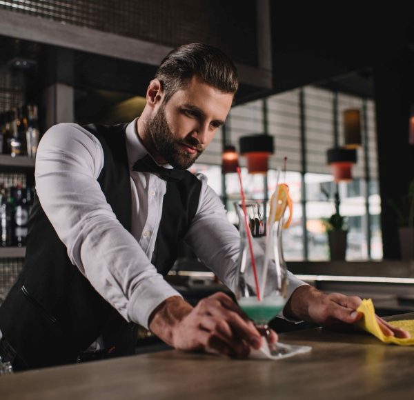 handsome bartender cleaning bar counter with rag